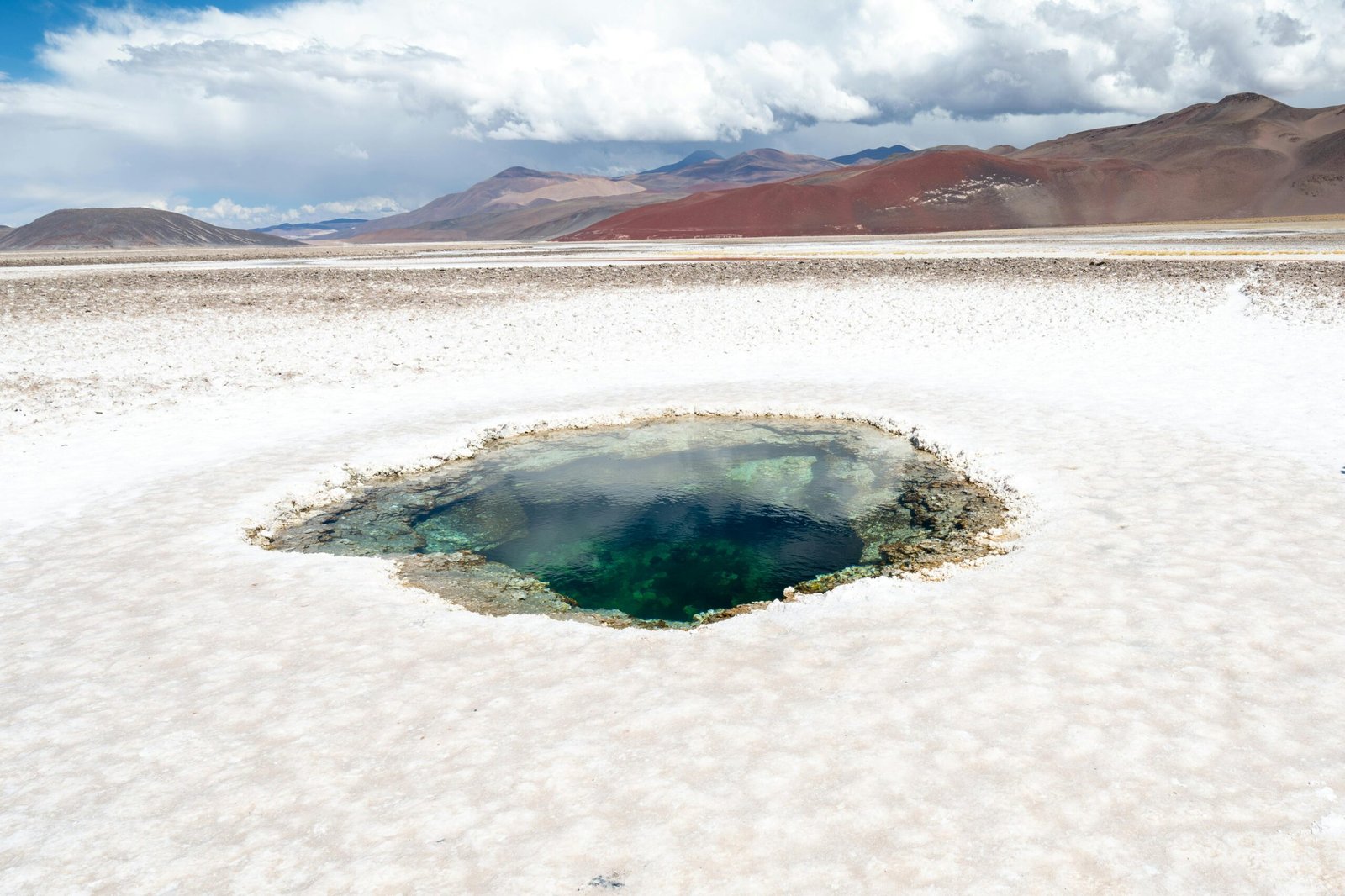 A stunning view of the Ojo de Agua at Salinas Grandes, Catamarca, with vibrant colors and majestic mountains.